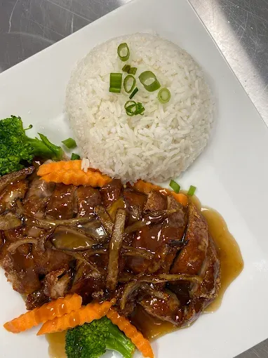 A Pada Thai dish with glazed protein, jasmine rice, broccoli, and carrots, plated fresh in the kitchen